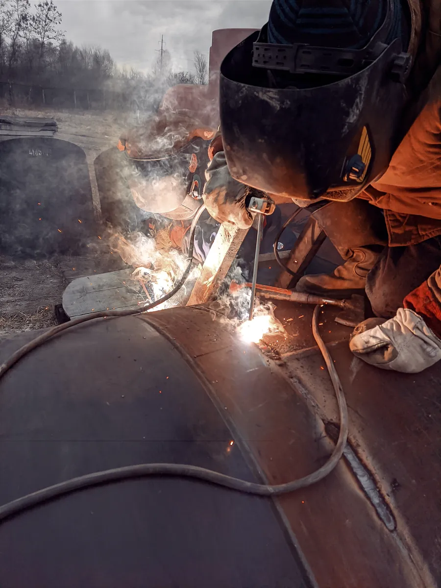 Welder working on a metal pipe with sparks