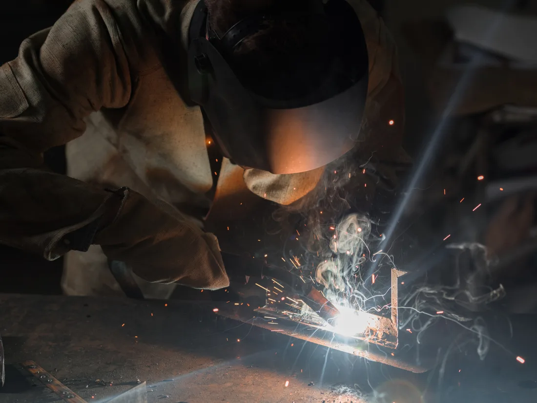 Welder welding metal with sparks flying