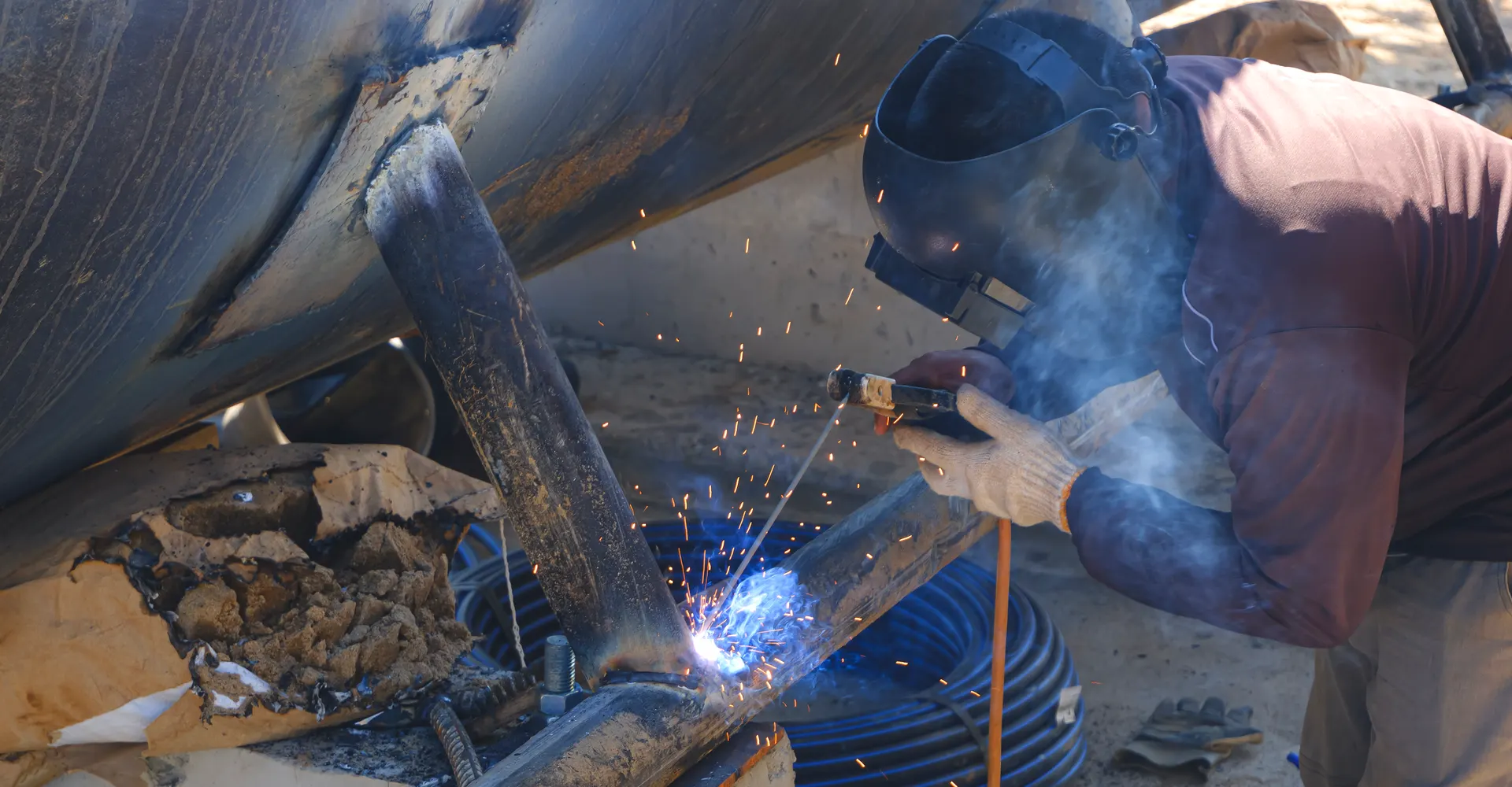 Welder welding a large metal base in the shop