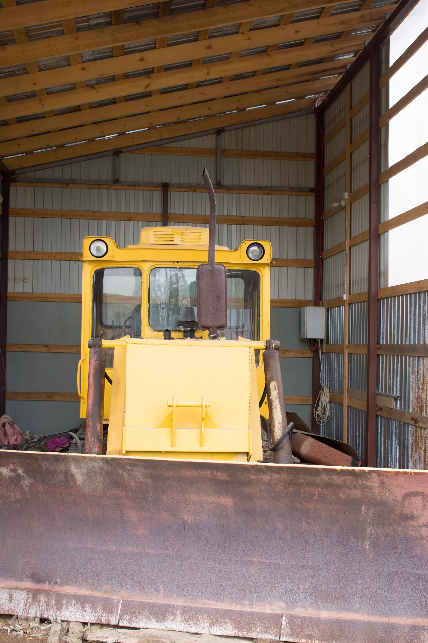 Yellow bulldozer parked in an equipment shed