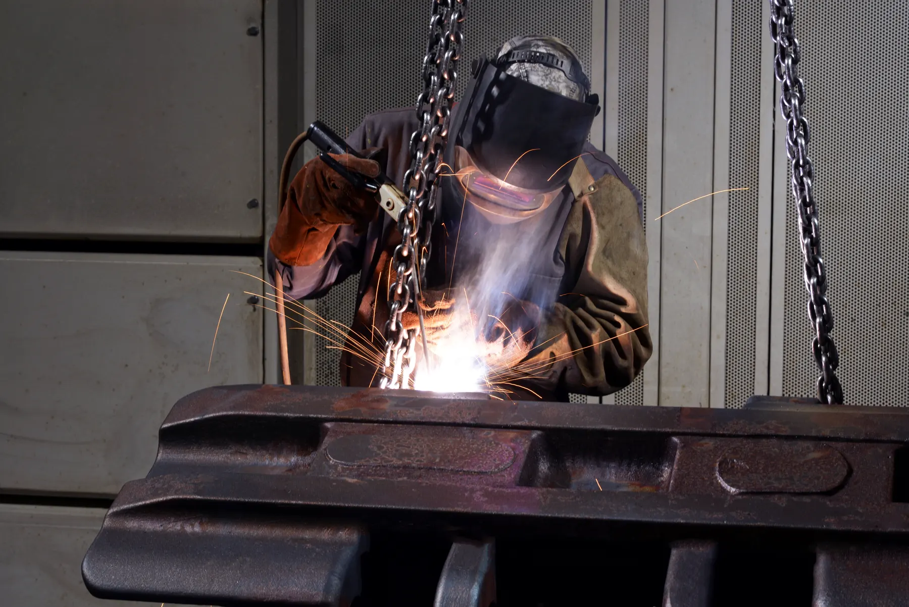 Welder joining a large heavy steel part in the shop